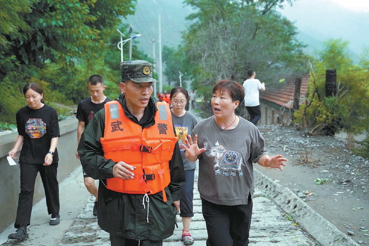 落坡岭社区党支部书记、主任孟二梅（右一）给刚赶到的武警指挥员介绍情况。王海欣 摄