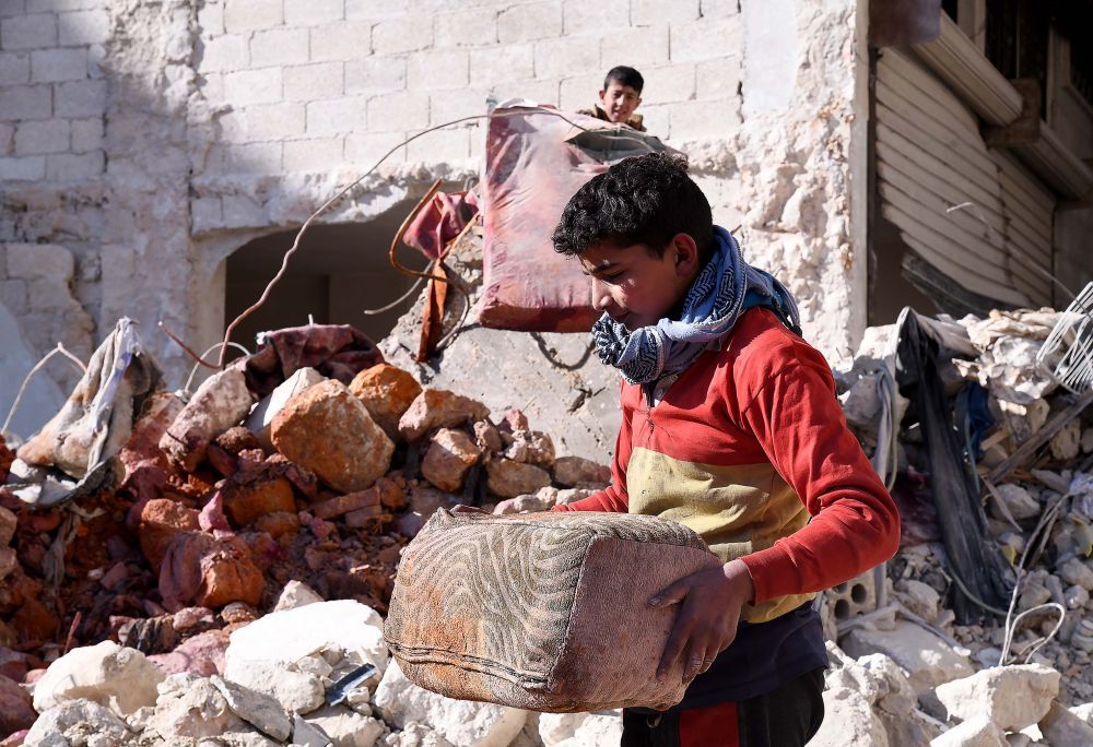 2月17日，在叙利亚阿勒颇，人们在地震后的废墟中搬运物品。新华社发