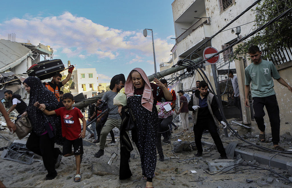 当地时间2023年10月17日，以色列空袭加沙地区，人们带着孩子匆忙逃离家园。