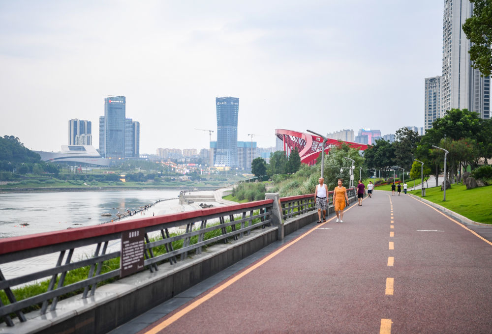 ↑人们在宜宾市三江口江边的绿道上散步。