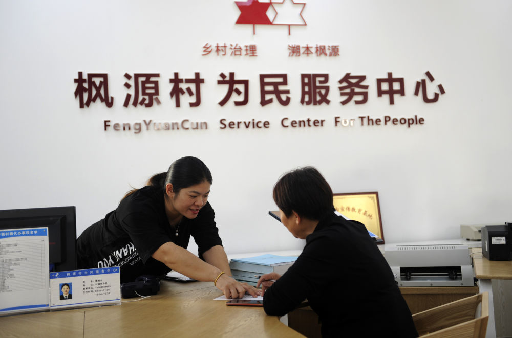 在浙江绍兴诸暨市枫桥镇枫源村，工作人员（左）在为民服务中心为村民办理事务（2020年10月31日摄）。