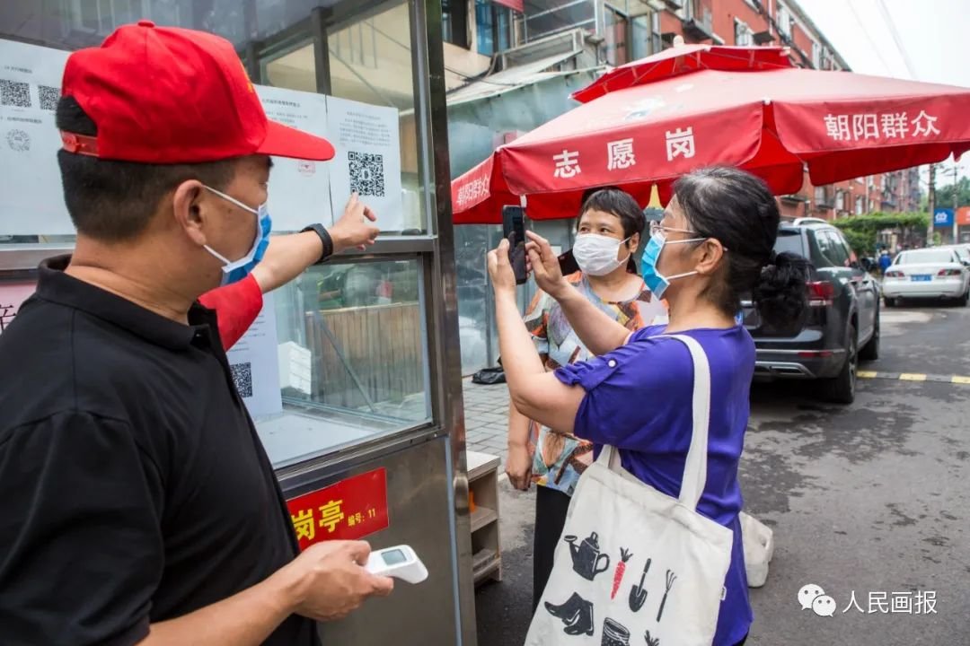 2020年7月3日,北京,朝阳区市场局人教科下沉干部在南路社区岗亭引导居民使用电子出入证。摄影 马耕平/人民画报