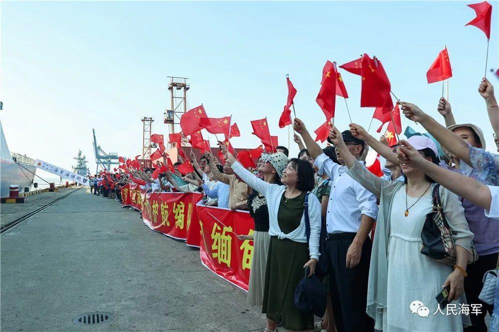 △图为码头欢迎人群挥舞五星红旗，热烈欢迎海军官兵。