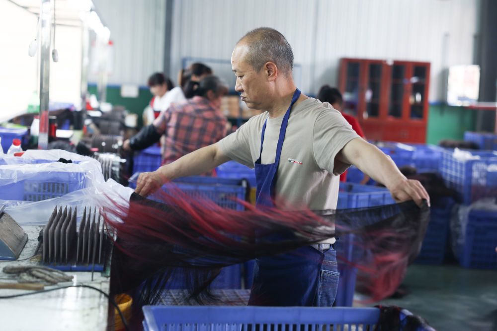 5月25日,工人在湖南邵阳美丽来发制品有限公司车间内生产假发