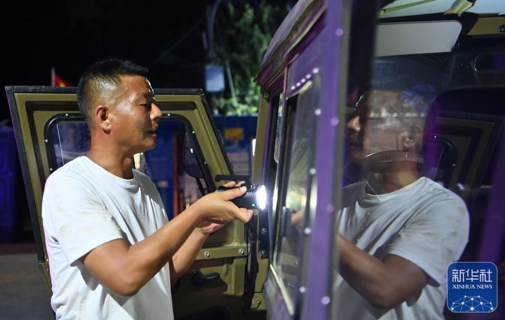 郝庆水从车内取出手电筒准备去巡视河堤（8月3日摄）。