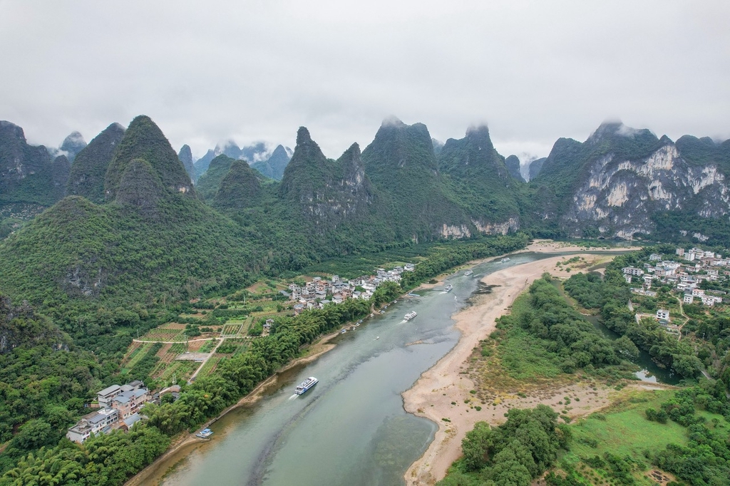 10月27日,广西桂林漓江两岸,雨雾在群山间如玉带般缠绕。青翠的江岸边,村舍在烟雨中若隐若现,呈现出了空灵缥缈的山水之象。舟行漓江上,游客如同置身画中。