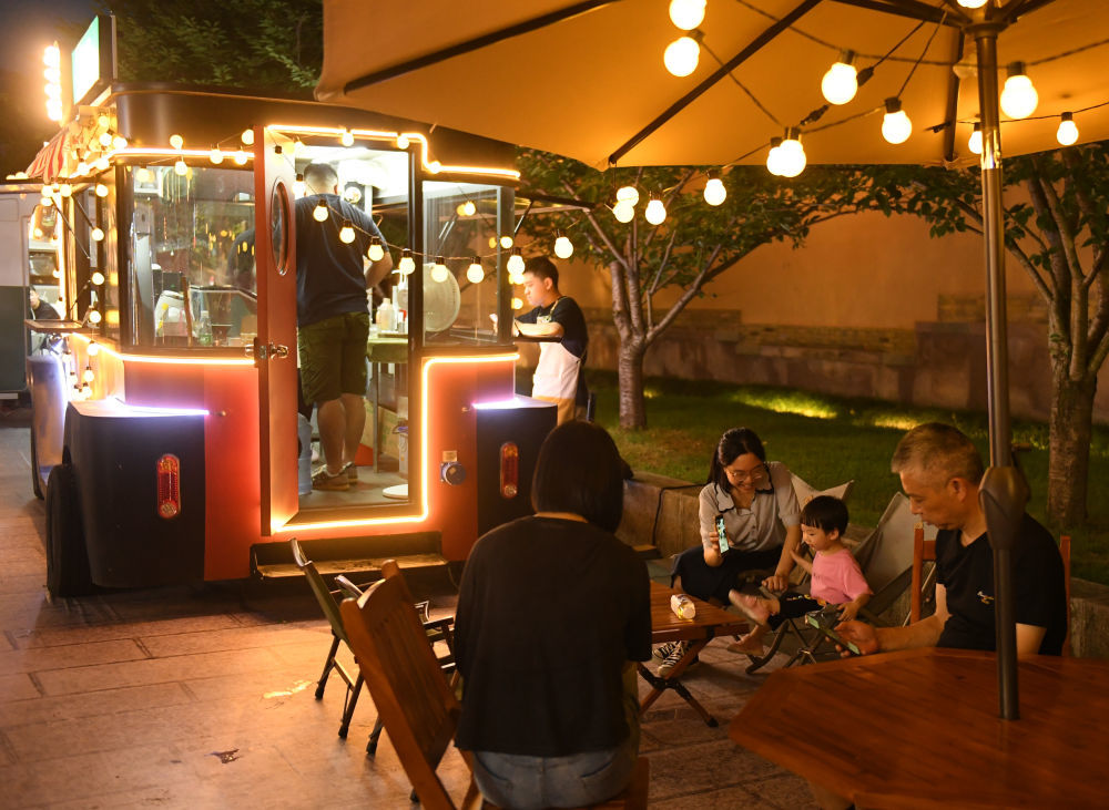 人们在台州府城一辆贩卖饮品的“巴士店铺”边休憩。