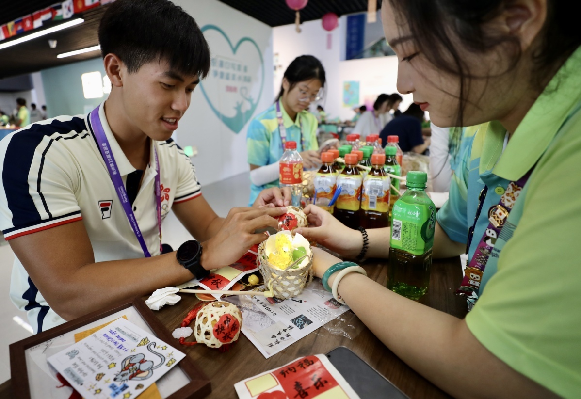 9月29日，中国香港运动员张颂灏（左）体验制作灯笼。中国日报记者 张威 摄