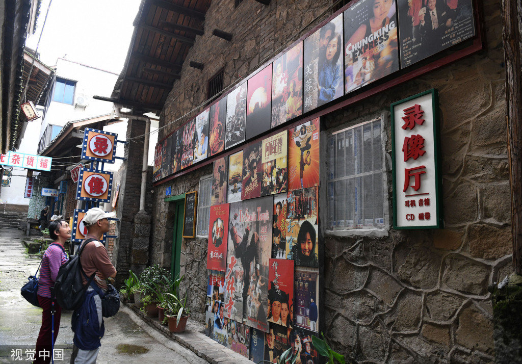 4月20日,重庆,綦江区东溪古镇内的老式书店吸引参观者驻足。东溪建镇1300多年,建场2200多年,是中国历史文化名镇、重庆十大古镇之一。为彰显古镇特色,东溪打造了一条独具特色的“80街”,将狭长街巷打造成创意怀旧集市,老重庆的街道和小巷以及展出的各种老物件吸引着不少市民前往感受“旧时光”。 中新社记者 周毅 摄