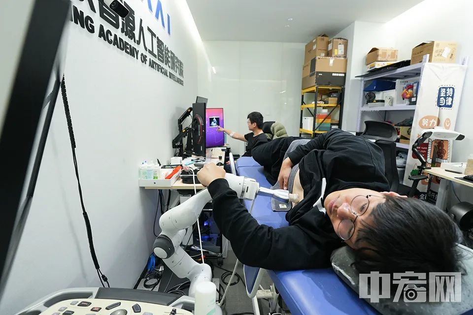 走进智源院大楼四层的一间小型会议室，仿佛来到医院的诊断室。只见一名工作人员侧卧在一张医疗床上，旁边一台机器触手正在这名工作人员的心脏部位的胸部表面来回移动。在床尾的电脑显示屏上，动态显示机器触手捕获到被测目标的心脏跳动画面，画面类似于超声波检测图像。这是智源院科研人员通过大数据模型开展的一个医疗检测科研应用项目。中宏网记者 富宇 摄