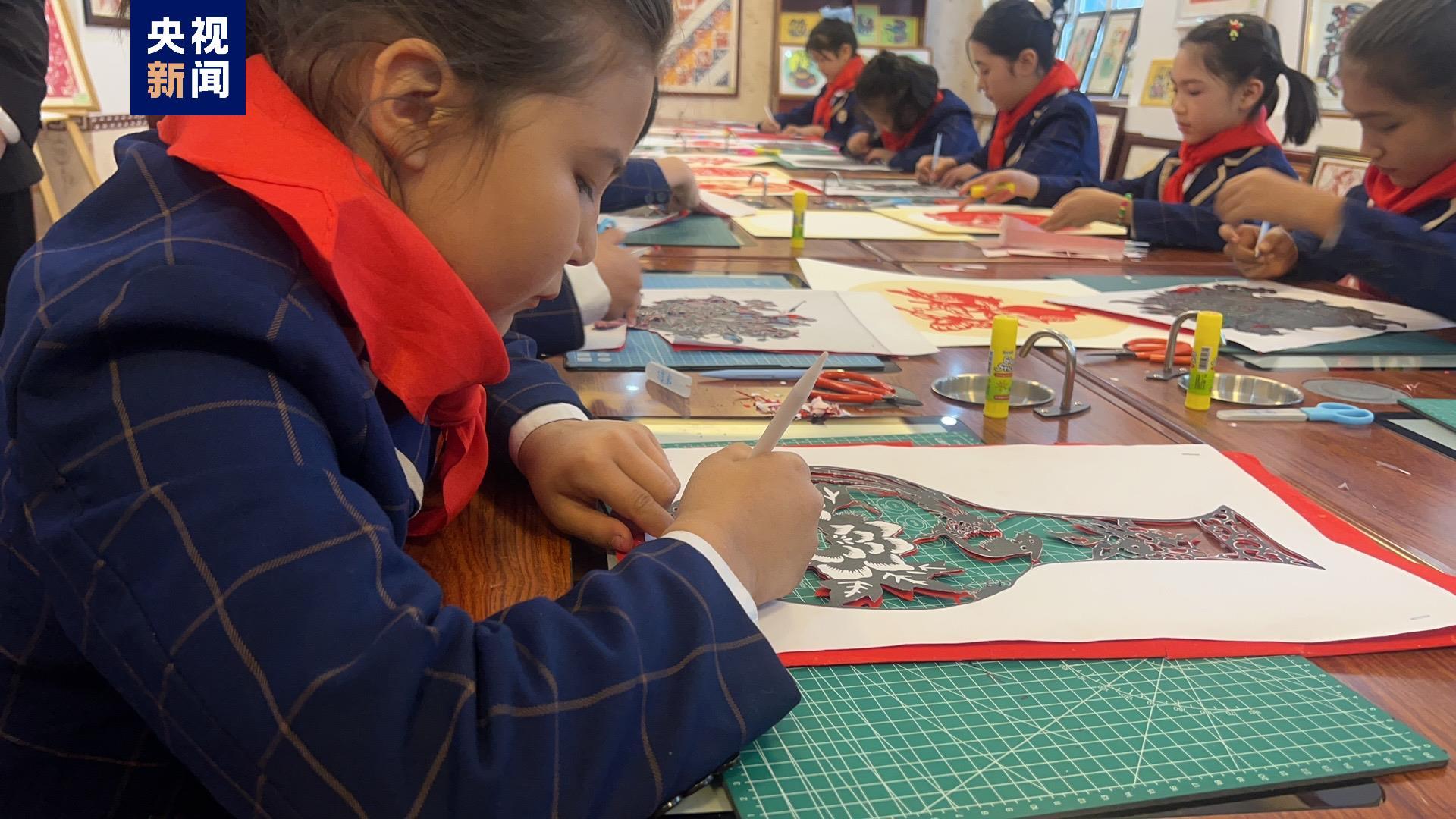 △明德小学剪纸工作室里，小朋友们正完成剪纸作品。