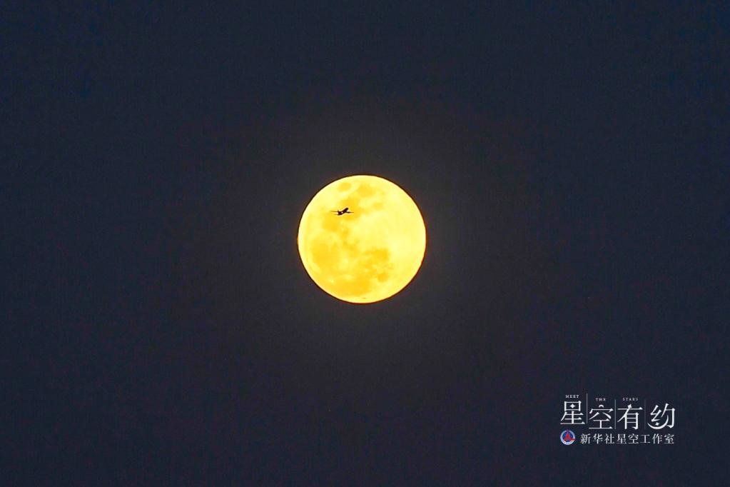 2019年2月19日，在云南省昆明市，一架飞机从年度“最大满月”前飞过。新华社记者蔺以光 摄