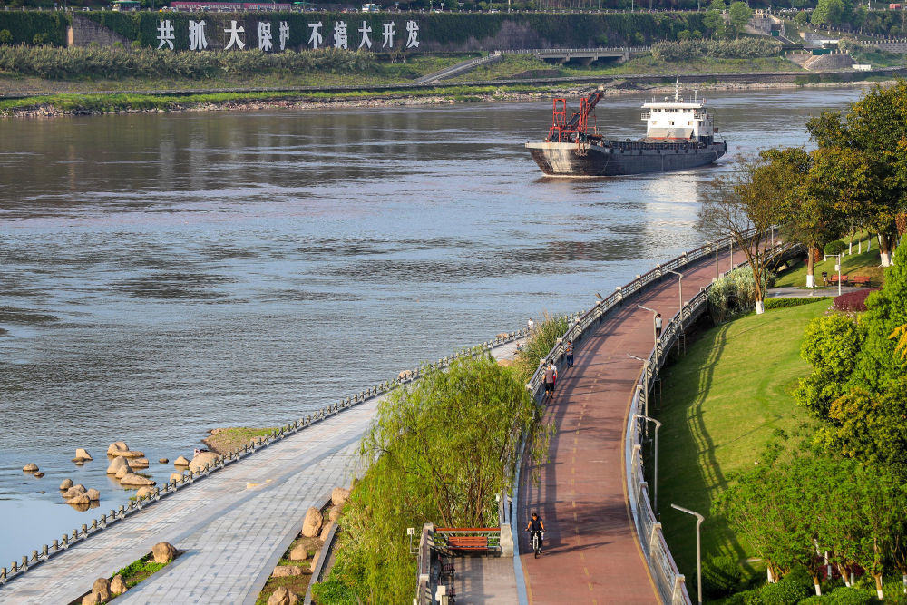 ↑在宜宾市三江口，市民徜徉在江边绿道上。