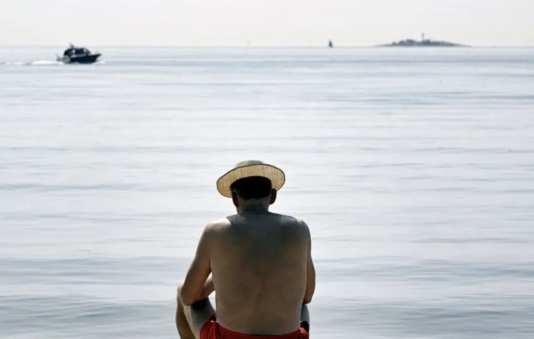 6月15日，一名男子在芬兰赫尔辛基的海边晒太阳 新华社/法新