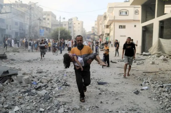一名加沙地带的巴勒斯坦男子抱走在空袭中受伤的女孩 图自：路透社