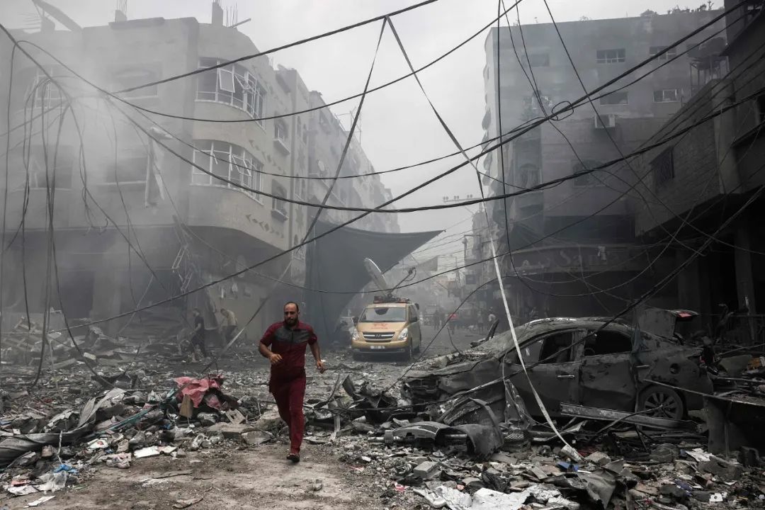当地时间2023年10月9日，巴勒斯坦加沙地带，以色列对贾巴利亚难民营的建筑物进行空袭后，一名巴勒斯坦人在废墟中奔跑