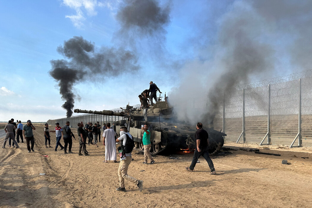当地时间10月7日，巴勒斯坦人与一辆被摧毁的以色列坦克合影。图自《纽约时报》