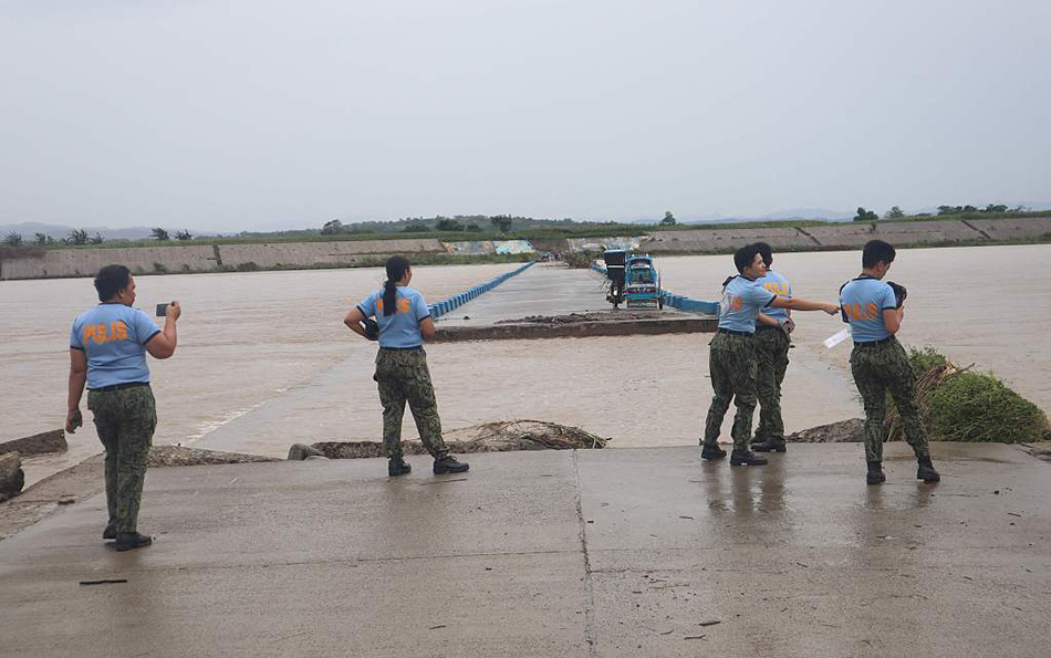 当地时间2023年7月26日,菲律宾伊莎贝拉省,台风“杜苏芮”带来暴雨导致河水泛滥,当地警察正在监视被水淹没的桥梁。
