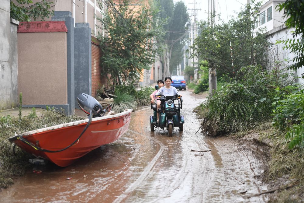 ↑8月3日，涿州市码头镇北高家庄村居民在街道上骑行。