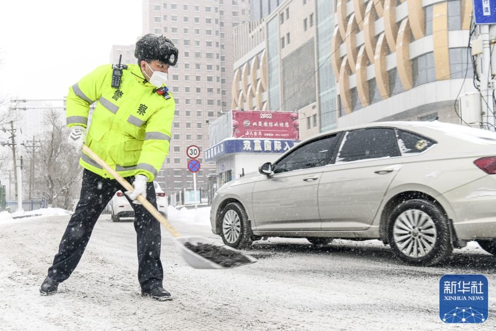 1月21日,在位于乌鲁木齐市的北园春副食海鲜市场附近,民警阿拉法特·胡加何买提在路面上抛洒炉渣,以防车辆打滑。新华社记者 王菲 摄