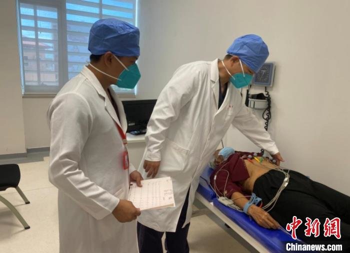 张大武(中)给患者做心电图。 援柬中医抗疫医疗队供图
