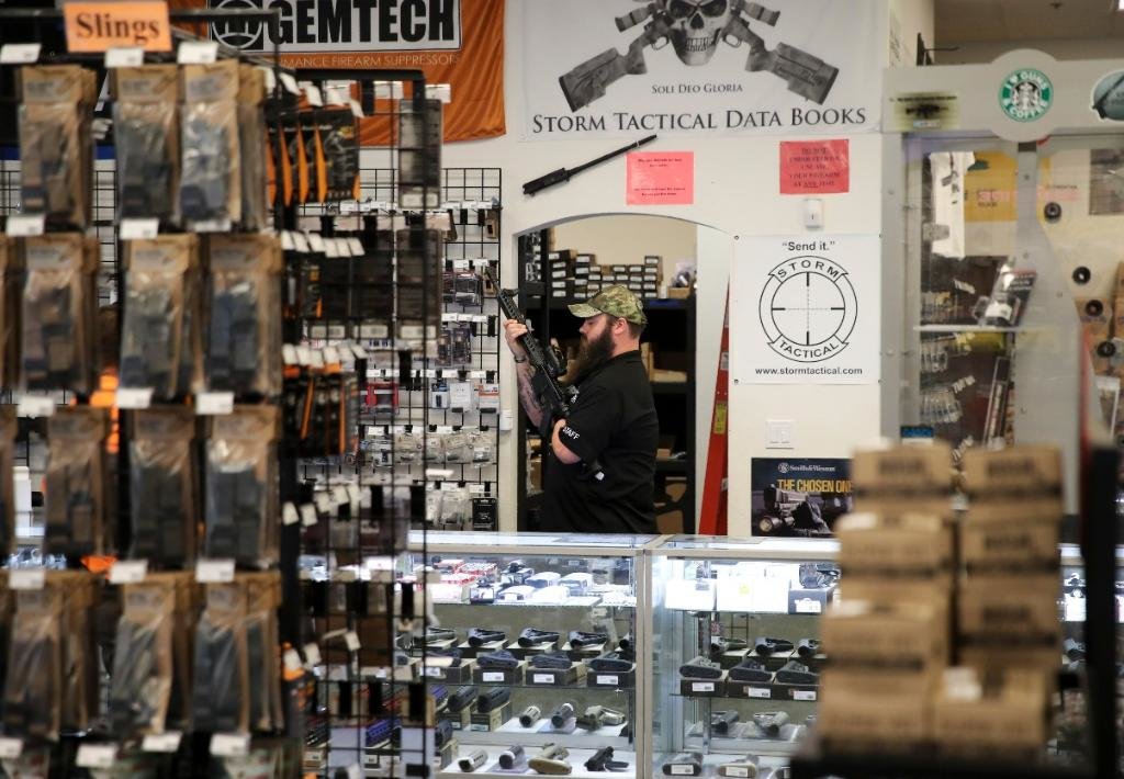 图为2017年10月4日拍摄的照片，在美国拉斯维加斯的“新前线”枪械商店，一名店员为顾客展示枪支。新华社记者 王迎 摄