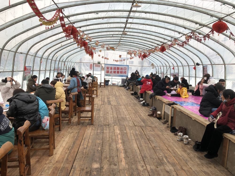 春节假期,一座塑料大棚内,土炕上的游客正在休息。新华社记者邹明仲 摄