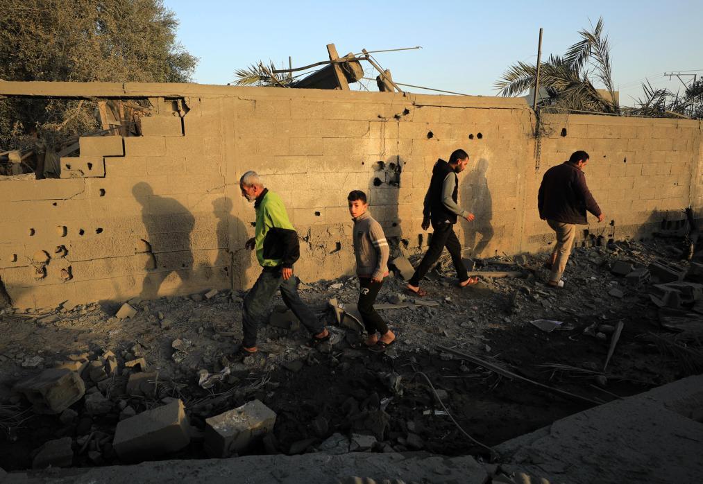 11月23日，在加沙地带南部的汗尤尼斯，人们从以军袭击后破损的街头走过。新华社发（亚西尔&middot;库迪摄）