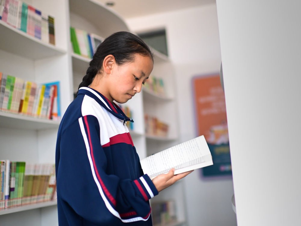 2024年6月18日，果洛西宁民族中学学生尼东拉毛在图书室看书。