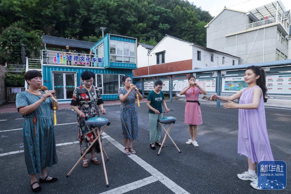 6月15日，杭州师范大学音乐学院的学生（右一）在三都镇镇头村指导村民进行空灵鼓、葫芦丝合奏。