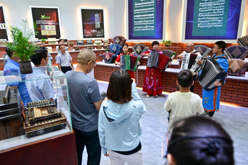 游客在新疆塔城市手风琴文化展示厅欣赏手风琴表演（7月24日摄）。