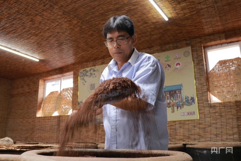 陈明友在翻动原料（央广网记者 周思杨 摄）