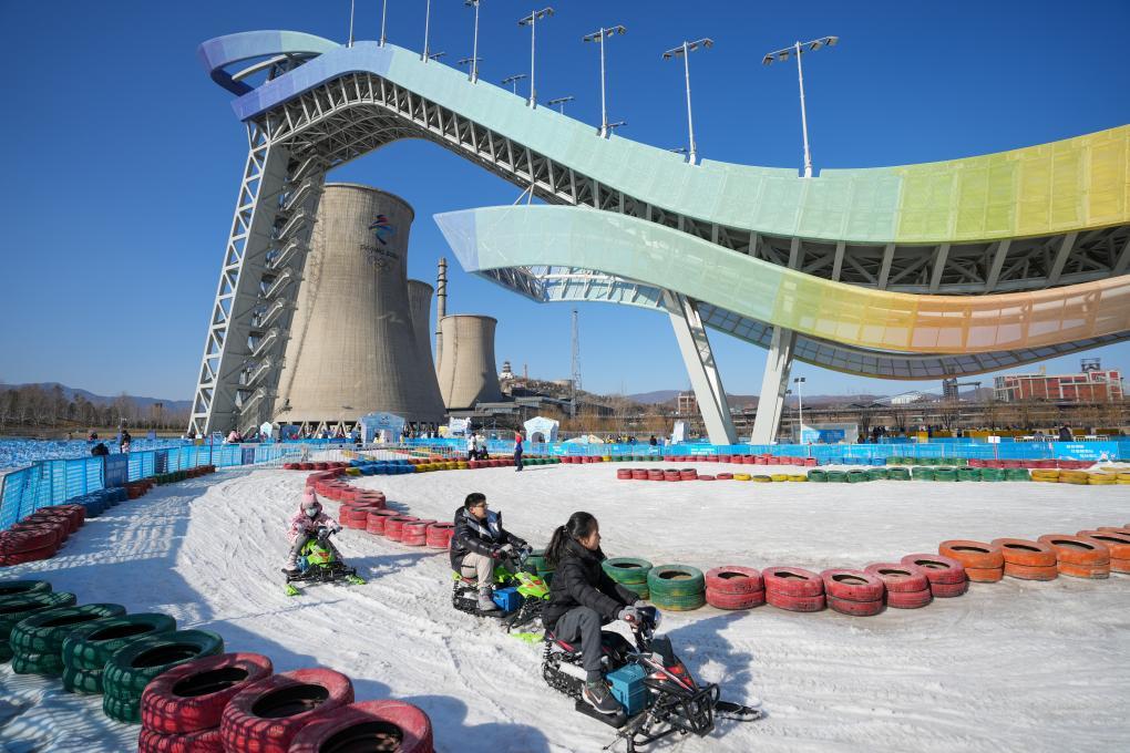 资料图:游客在首钢滑雪大跳台下的首钢园冰雪汇体验雪上游乐项目