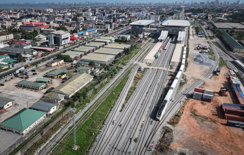 2024年3月2日，在尼日利亚拉各斯，列车从拉伊铁路莫博拉吉·约翰逊火车站驶出（无人机照片）。2021年6月，在共建“一带一路”倡议指引下，由中国土木工程集团有限公司（中土集团）承建的连接拉各斯和伊巴丹的铁路（拉伊铁路）正式通车运营，干线全长约157公里，支线长约7公里，采用现代化铁路标准，设计时速150公里。新华社记者 韩旭 摄