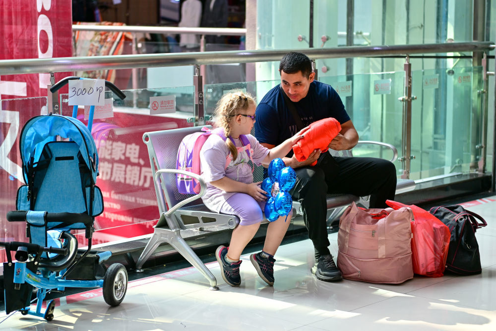 在中哈霍尔果斯国际边境合作中心，来自哈萨克斯坦的游客在购物后休息（7月27日摄）。
