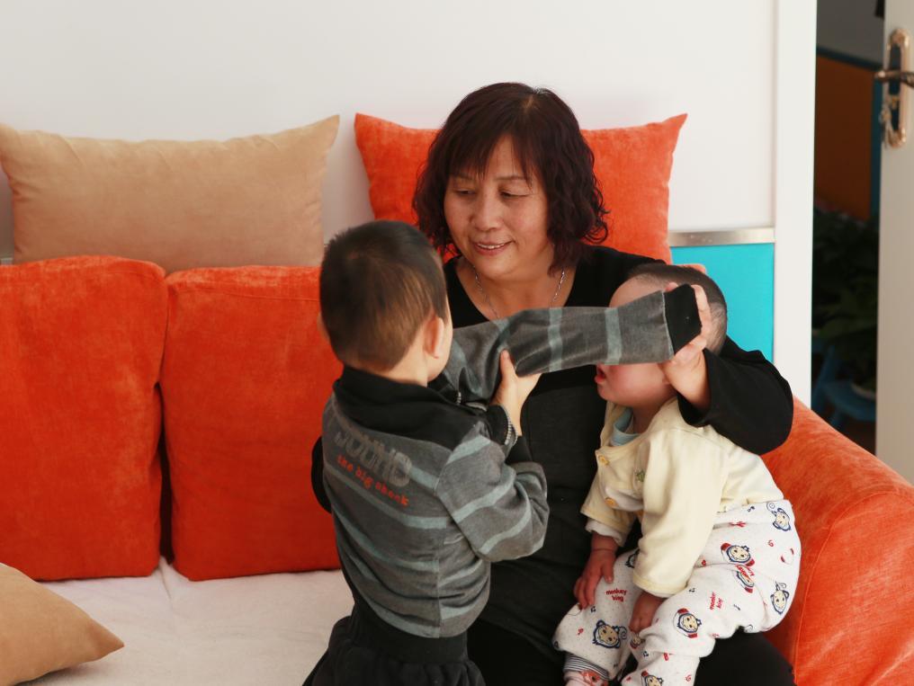 2017年11月3日，内蒙古呼和浩特市儿童福利院里，“爱心妈妈”景凤英抱着两个孩子。新华社记者 王婧嫱 摄