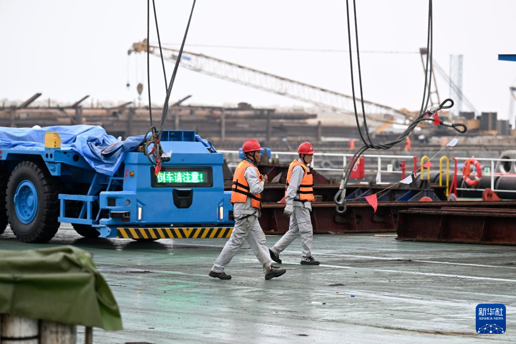 6月21日，工作人员从秘鲁钱凯港码头操作区的具备自动驾驶技术的电动集装箱卡车旁走过。 新华社记者 李木子 摄