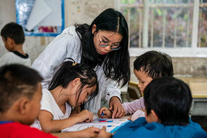 在云南省文山州文山市马塘镇新开田村委会新开田一队，志愿者杨红非在“少年儿童之家”教孩子们绘画（2022年8月9日摄）。