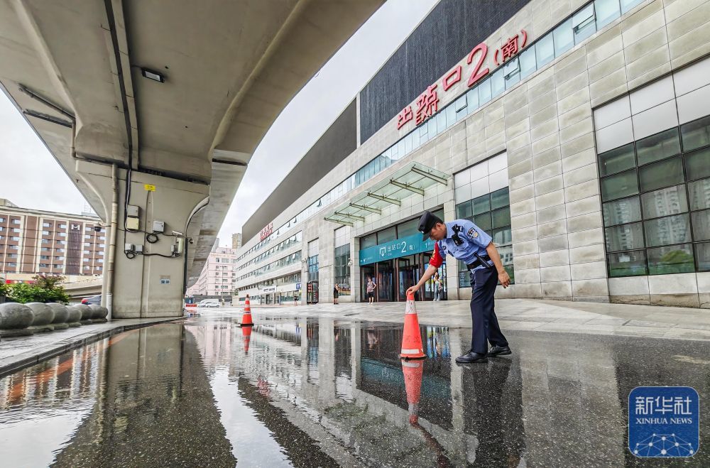 7月28日，在沈阳北站，沈阳铁路公安处民警在出站口附近的积水处设立警示标志。新华社发