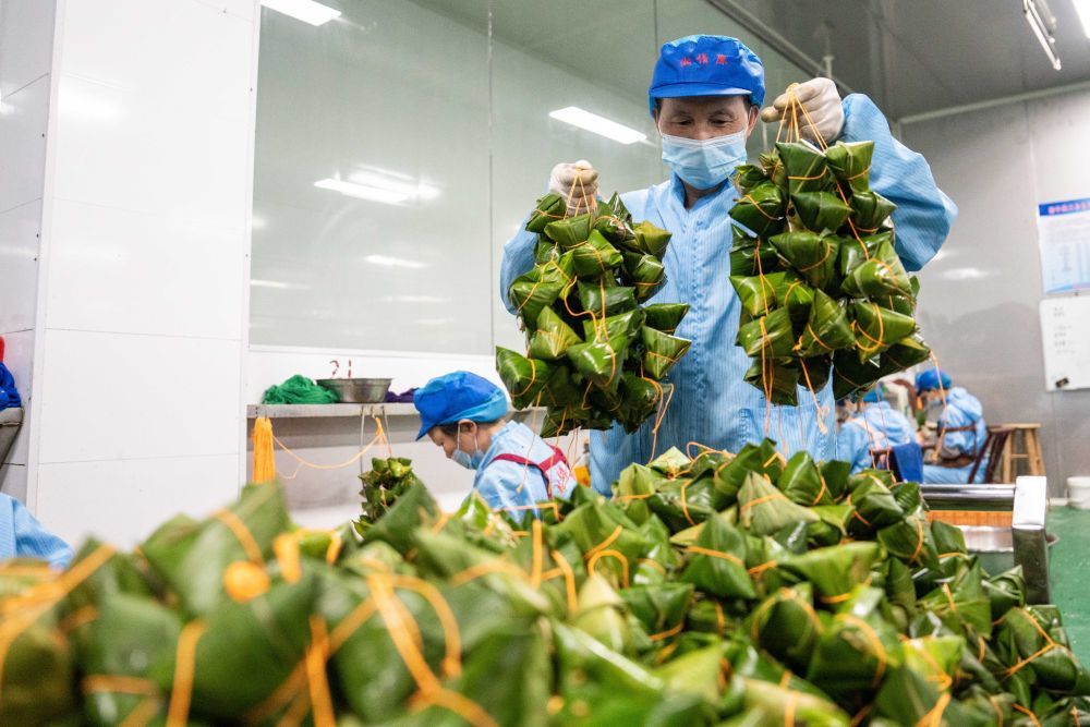 6月5日，在浏阳市关口街道道源湖村一家粽子生产车间，工人整理刚包好的粽子。