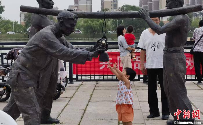 图为运河玖库河边,小女孩伸手触摸雕塑。郎朗 摄