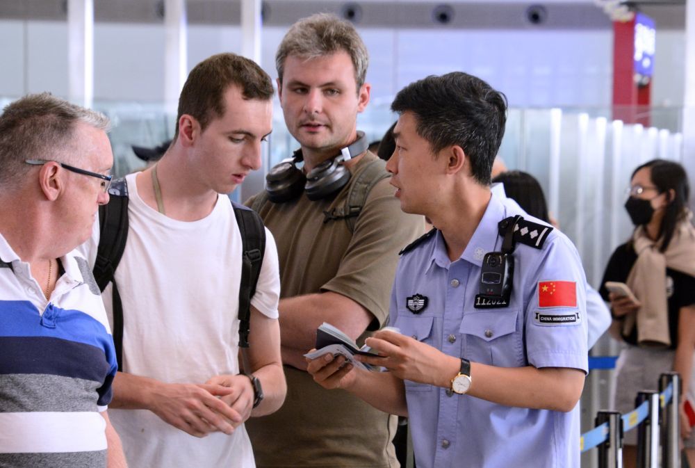 7月10日，北京首都机场边防检查站的民警回答外籍旅客的免签入境问题。在“72/144小时过境免签”等系列便利外籍人士来华的政策推动下，外籍人士中国行持续升温。新华社记者李欣摄