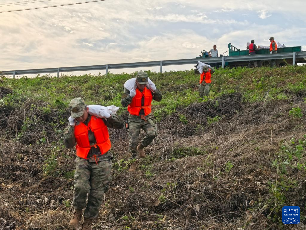 7月8日，南部战区空军航空兵某师官兵在湖南省岳阳市华容县团洲垸钱团间堤搬运沙袋封堵渗水点。新华社发（向博文 摄）