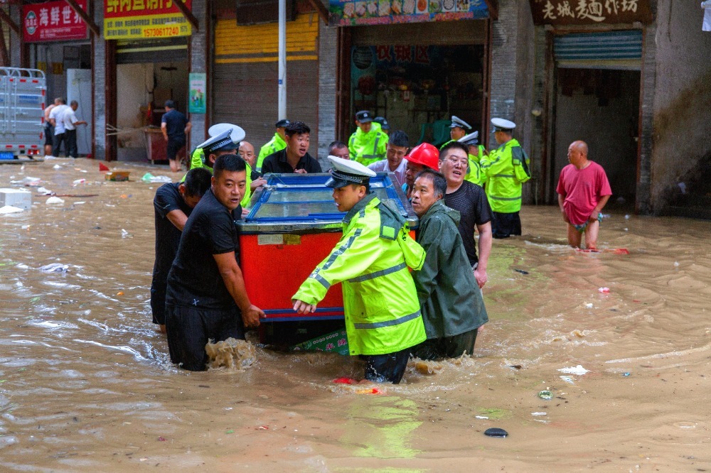 ▲7月11日，巫溪县宁河街道，工作人员在水中帮市民转移物资。巫溪县县委宣传部供图