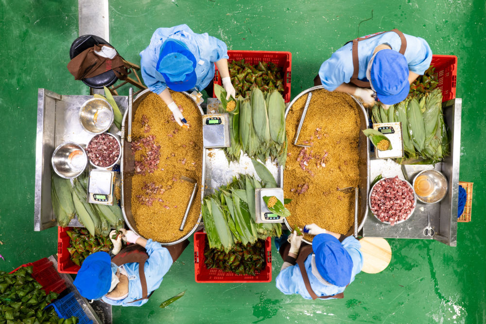 6月5日，在浏阳市关口街道道源湖村一家粽子生产车间，工人在包粽子（无人机照片）。