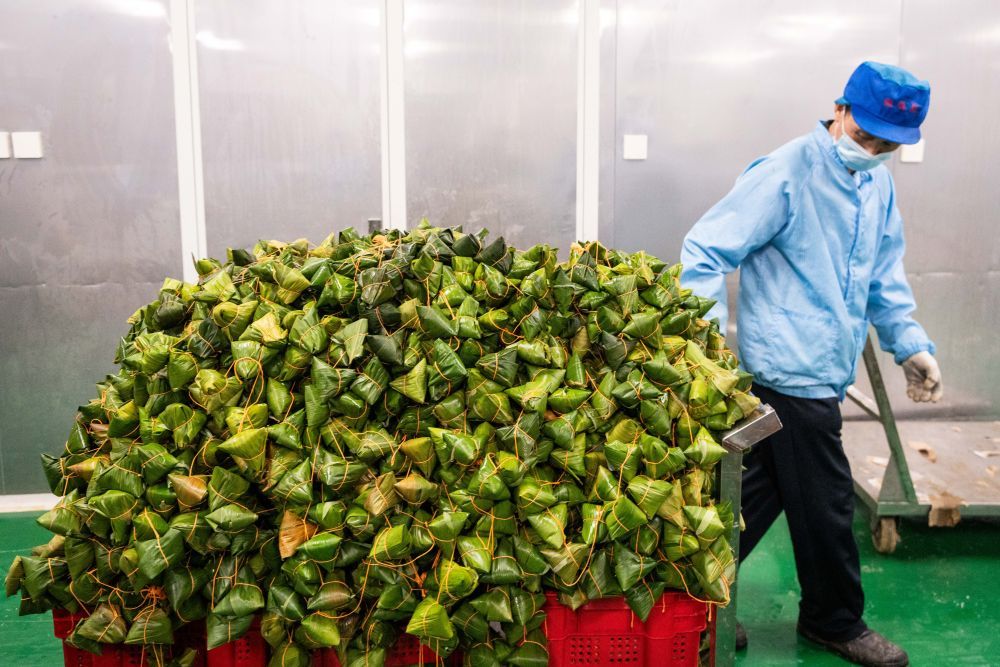 6月5日，在浏阳市关口街道道源湖村一家粽子生产车间，工人在运输粽子。