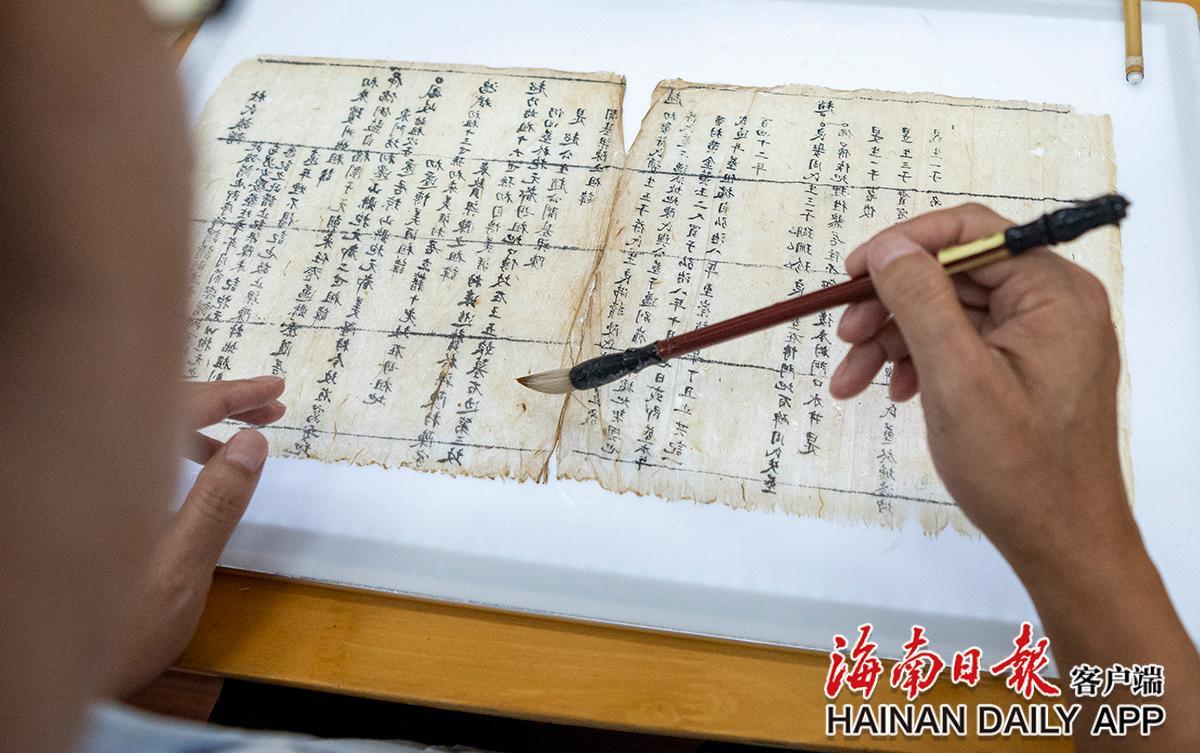 黄文锋将修复后的古籍书页，粘贴、加固到新纸上。海南日报记者袁琛 摄