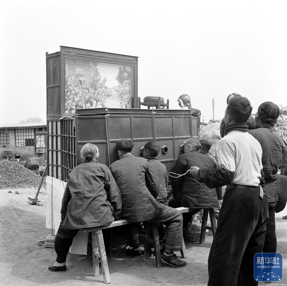 1957年4月，人们在北京蟠桃宫庙会上观看拉洋片。新华社发