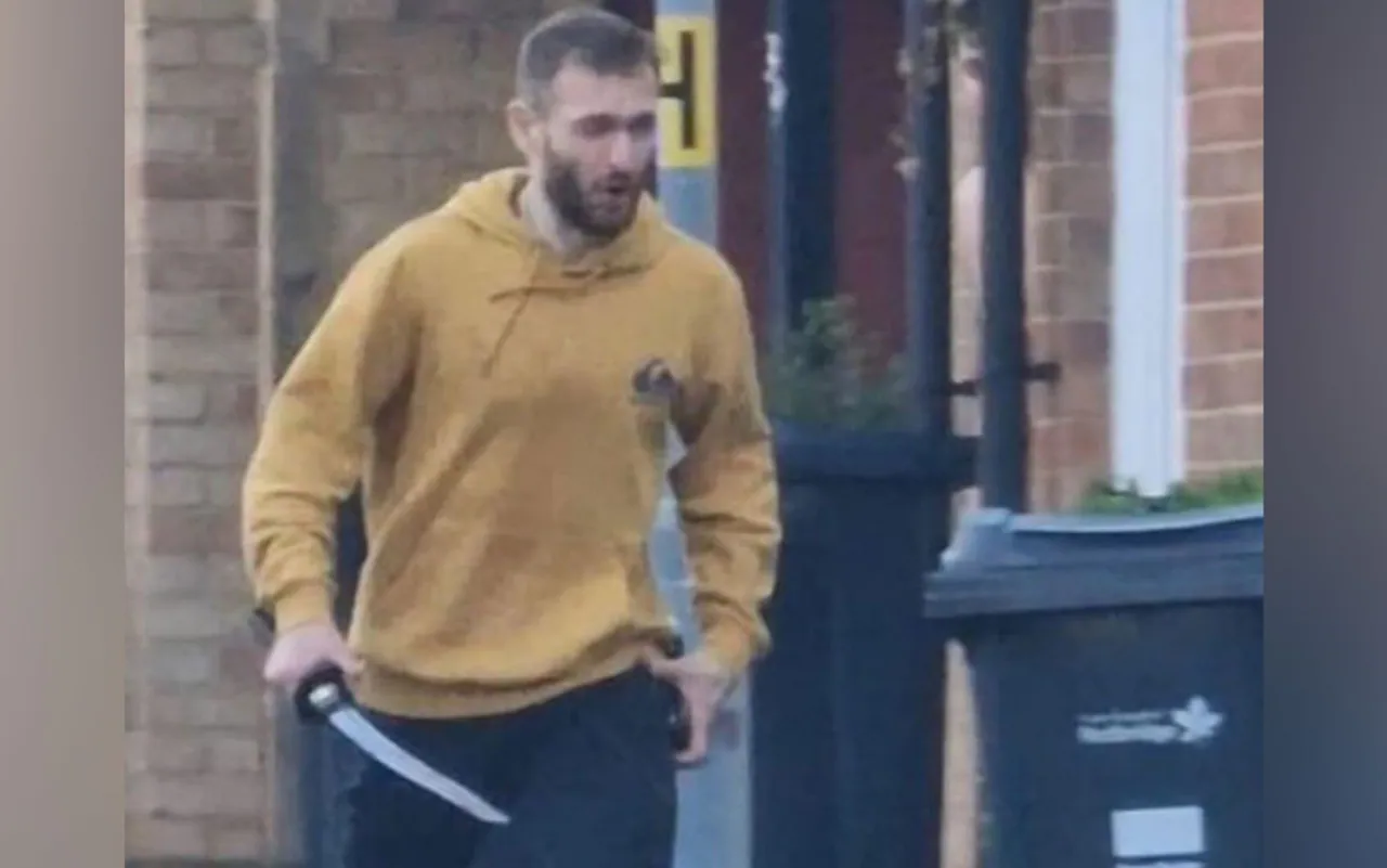 英国《每日电讯报》称，社交媒体视频截图显示一名身穿黄色连帽卫衣的男子“持剑”在街道上行走 图源：英媒引自社交媒体