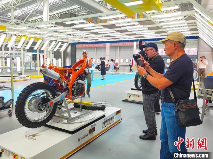 中亚媒体代表们在霍尔果斯中金科技产业园的摩托车生产车间采访。主办方供图